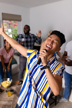 Happy diverse friends dancing and karaoke singing with microphone at home