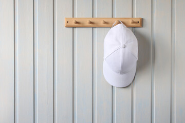 white baseball cap is hanging on a hanger.