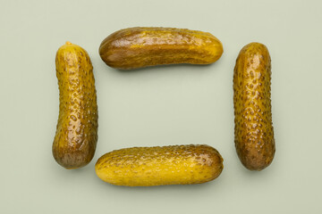 Frame made of pickled cucumbers on green background