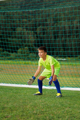 A young footballer in a green uniform on goal