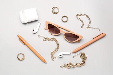 Stylish sunglasses with beautiful jewellery and earphones on grey background