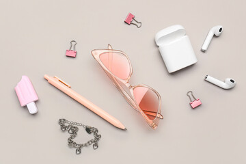 Stylish sunglasses with stationery supplies and earphones on grey background