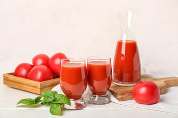 Glasses and jug of tasty tomato juice on table