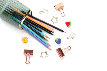 Cup with colorful pencils and paper clips of different shapes on white background
