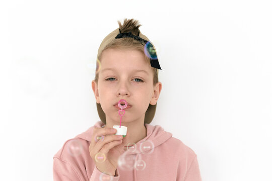 Horizontal portrait of boy blowing bubbles against white wall background