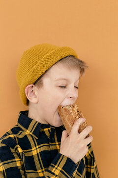 Portrait of very hungry young fellow biting bread with wide open mouth