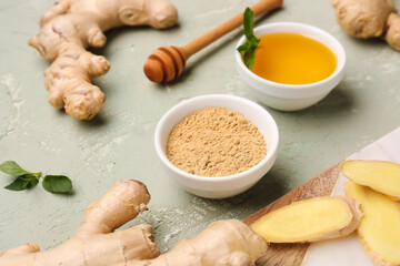 Fresh ginger roots and bowl with dried powder on grey background