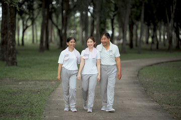Fototapeta premium Beautiful Asian woman taking her father and mother to exercise in the park happily, with a smile. Young woman invites parents to exercise, warm family, good health. concept health care life insurance.