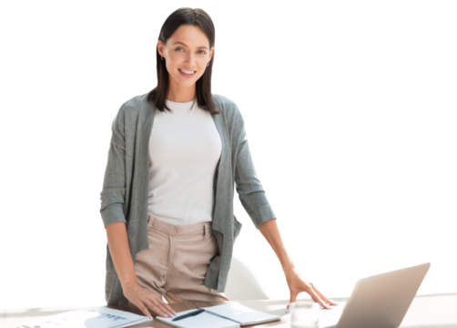 Confident young businesswoman with a friendly smile standing behind her desk on a transparent background looking at the camera.