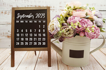 September 2023 monthly calendar with green leaf decoration on wooden background - obrazy, fototapety, plakaty