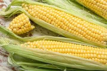 Fresh corn cobs on weathered wooden table, closeup