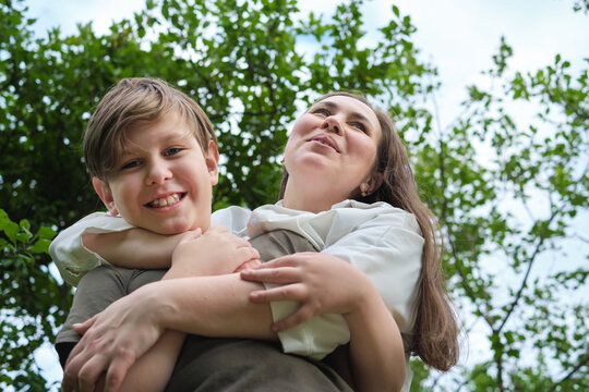 Authentic image from a garden photoshoot, capturing a mother and her pre-teen son in a genuine laugh, portraying the beauty of natural photography