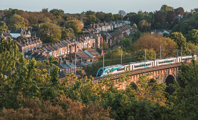 townhouses standing beside the railway on the viaduct with a running train in Durham, UK