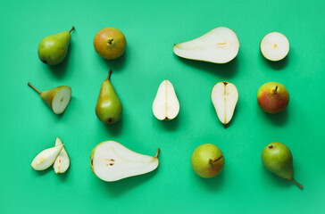 Different types of ripe pears on green background