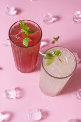 Summer lemonades with ice and mint in glass glasses top view on pink background.
