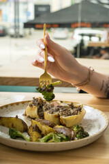 Close up of a fork in a woman's hand over a plate with delicious food in a restaurant