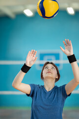 Sporty young woman playing volleyball. Professional female volleyball player throws the ball over...