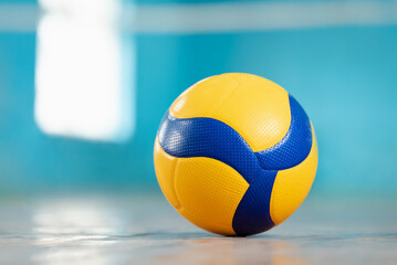 Volleyball blue and yellow ball on the floor in the gym. Concept of sport training, physical...