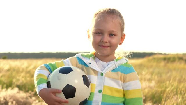 little girl daughter smiling looking camera.close-up happy daughter ball hands. face happy child football field. happy family. soccer player childhood dream. active sports recreation nature. chidhood