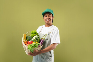 Potrait of young asian farmer man holding fresh vegetable, isolated on green background