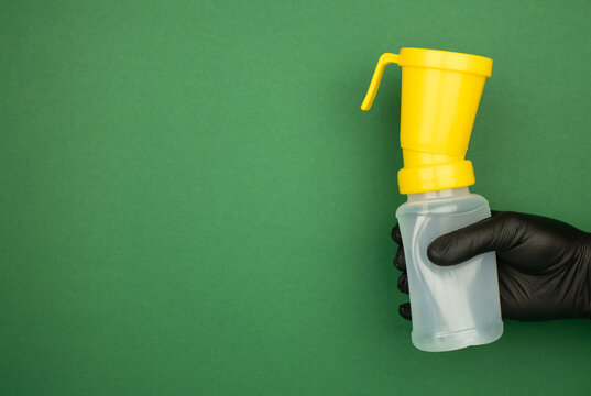 Teat dip cup for udder cow disinfection in farmer hand on green background, banner. Milking procedure concept