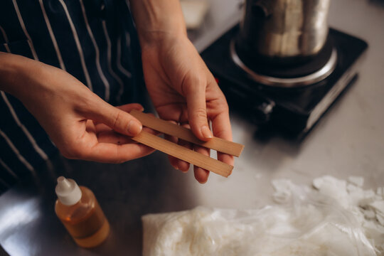 A woman holds a wooden wick in her hands for making a candle