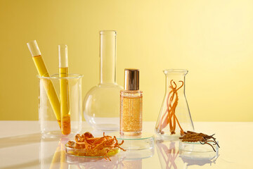 A serum bottle unbranded displayed on yellow background with some lab equipment containing...
