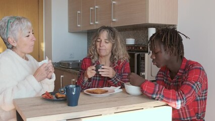 Mature lesbian couple enjoying having breakfast with their son at home.