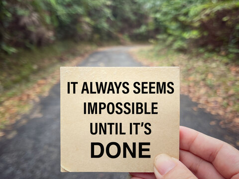 Motivational and inspirational wording. It Always Seems Impossible Until It’s Done written on a notepad. With blurred styled background.