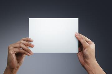 Woman two hands holding a blank paper on gray background.