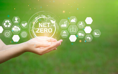 In the hand there is a carbon neutral NET ZERO icon. The concept of net zero carbon emissions and...