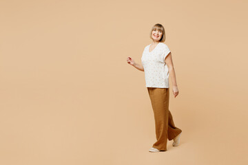 Full body side view smiling happy blonde elderly woman 50s years old she wearing casual clothes...