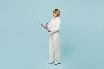 Full body employee business woman 50s wear white classic suit glasses formal clothes clipboard with paper account documents write isolated on plain pastel blue background. Achievement career concept.