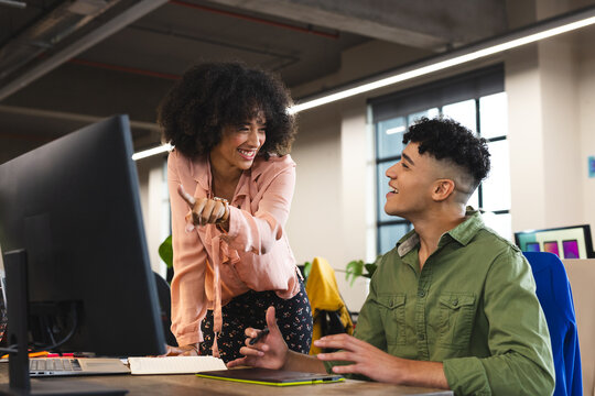 Happy diverse female and male colleagues in discussion at computer in office