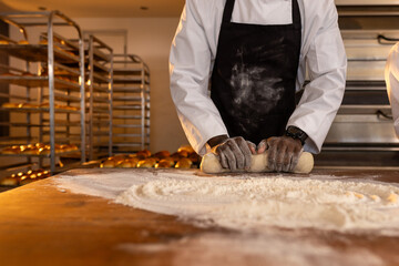 African american male baker with smartwatch in bakery kitchen kneading dough, copy space
