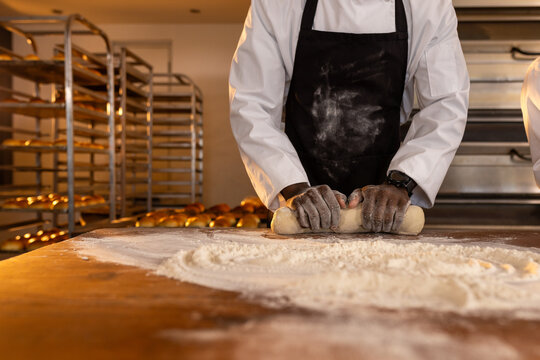 African american male baker with smartwatch in bakery kitchen kneading dough, copy space