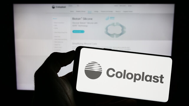 Stuttgart, Germany - 07-24-2023: Person holding cellphone with logo of Danish healthcare company Coloplast AS on screen in front of business webpage. Focus on phone display.