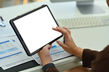 Closeup shot of professional businesswoman using digital tablet and working on sales statistics document at desk