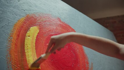 Female artist painting on canvas with bright paints in art studio