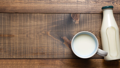 Milk cup and bottle on wooden table. Top view with copy space