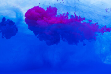 Close up of blue and pink ink in water with copy space background