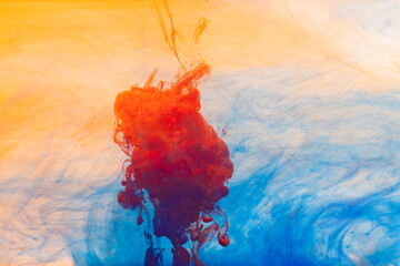 Close up of orange, yellow and blue ink in water with copy space background