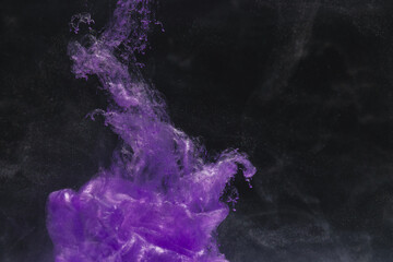 Close up of bright purple ink in water with copy space on black background