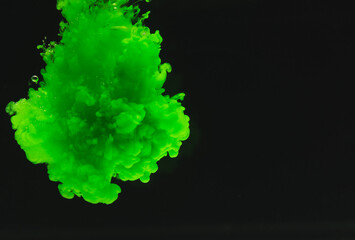 Close up of bright green ink in water with copy space on black background