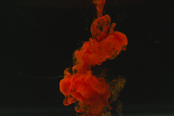 Close up of bright red ink in water with copy space on black background
