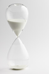 Close up of hourglass with white sand and copy space on white background