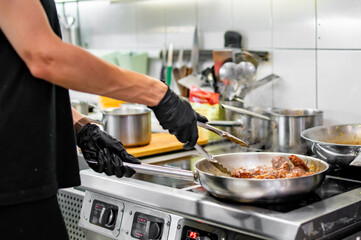 chef cooking chicken wings in a sauce in the kitchen