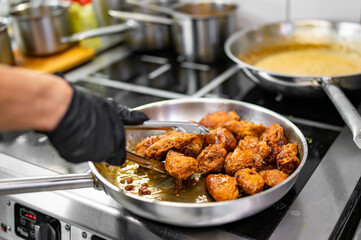 chef cooking chicken wings in a sauce in the kitchen