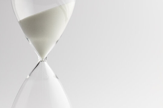 Close up of hourglass with white sand and copy space on white background