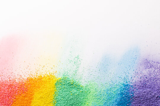 Close up of stripes of rainbow coloured sand and copy space on white background
